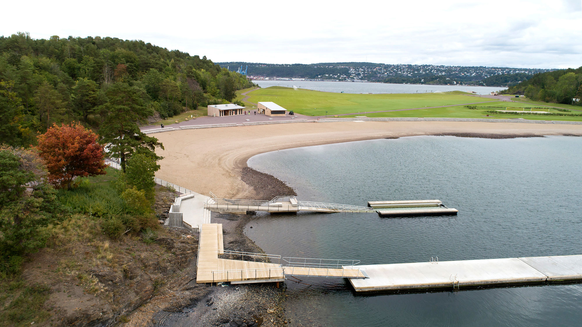 Skrått dronebilde av badeanlegget med tilrettelagt badebinge på Nye Langøyene, med badestranden og gressletten i bakgrunnen. Foto: Asplan Viak/Jostein Thorvaldsen