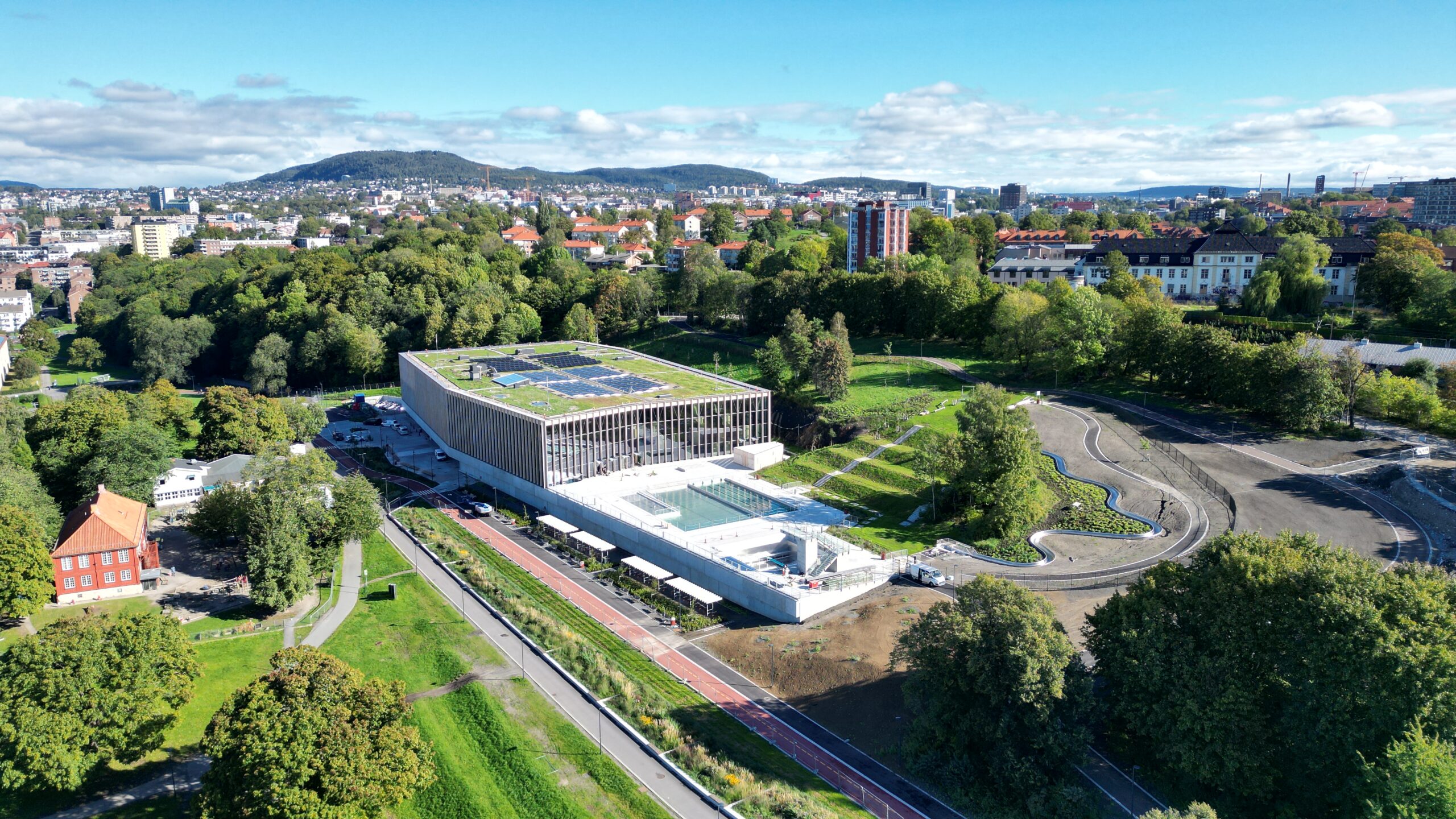 Dronefoto tatt skrått ovenfra som viser Tøyenbadet med grøntarealene rundt.